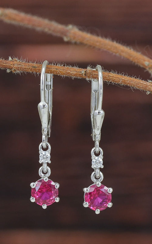 A pair of silver leverback earrings with round pink gemstones and small clear accent stones.