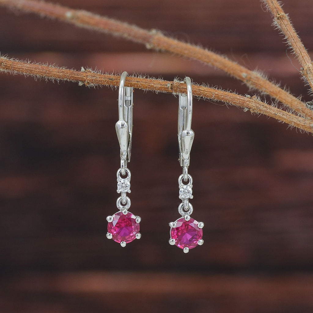 A pair of silver leverback earrings with round pink gemstones and small clear accent stones.