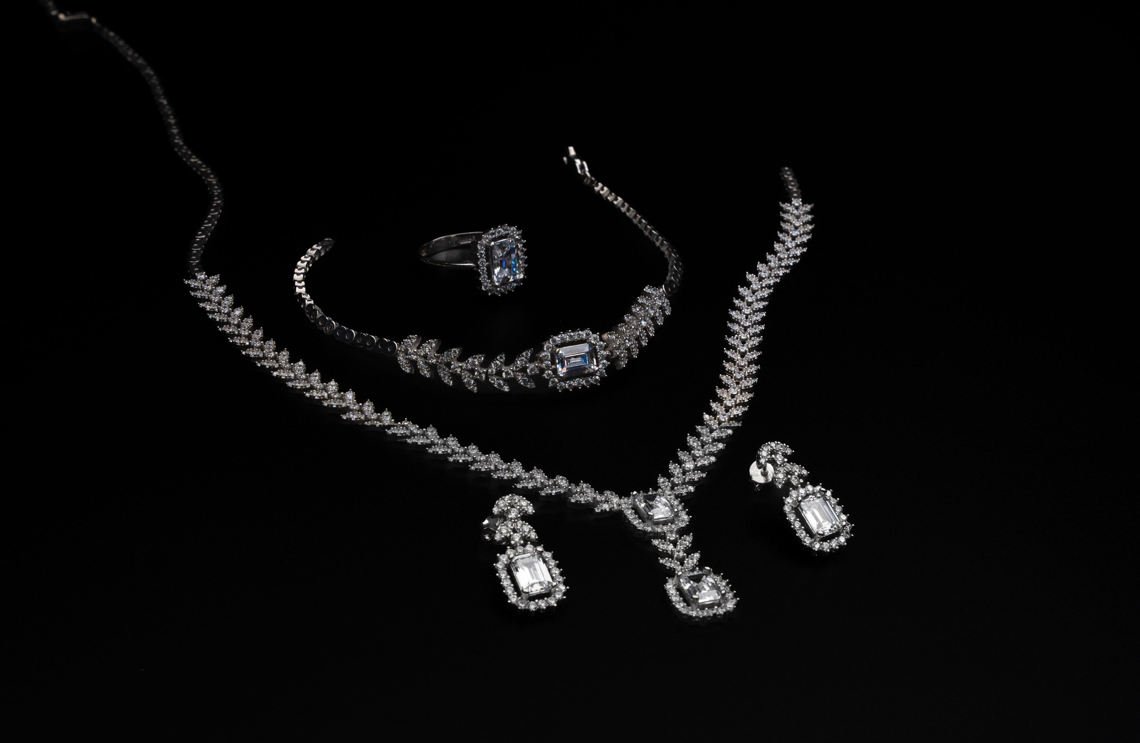 Jewelry set including a necklace, ring, and earrings on a black background