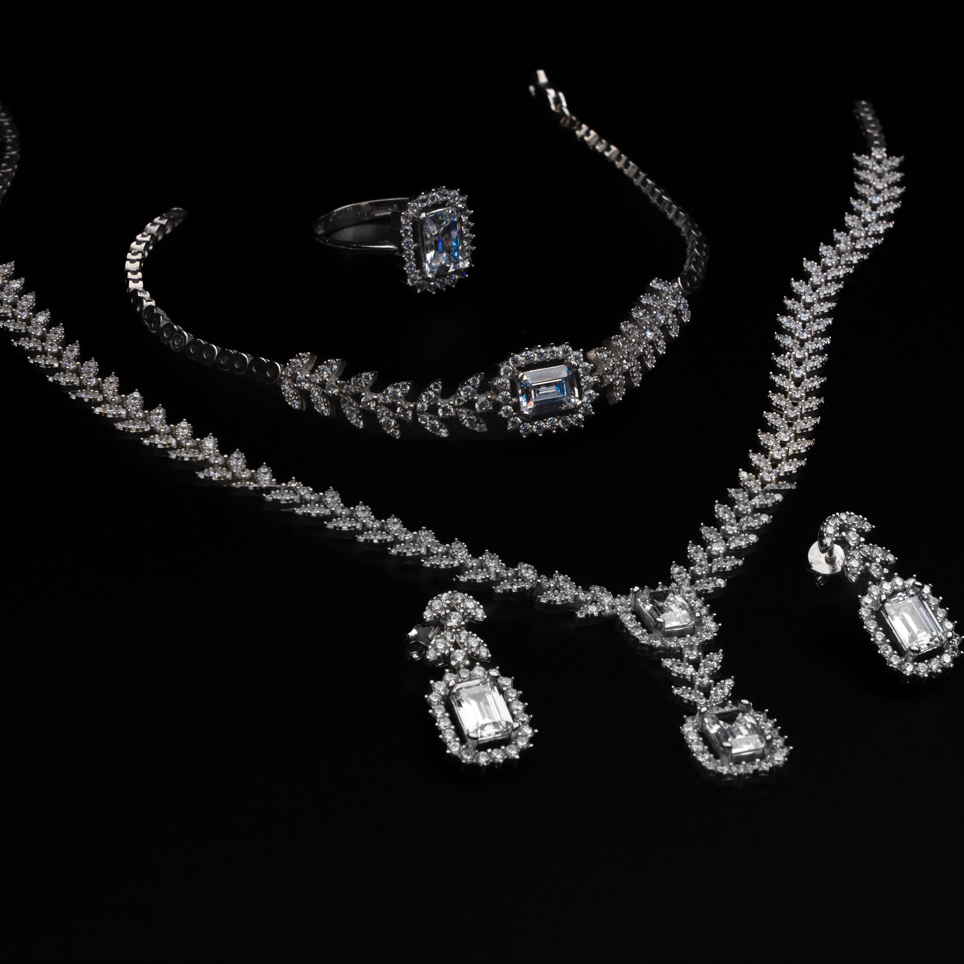 Jewelry set including a necklace, ring, and earrings on a black background