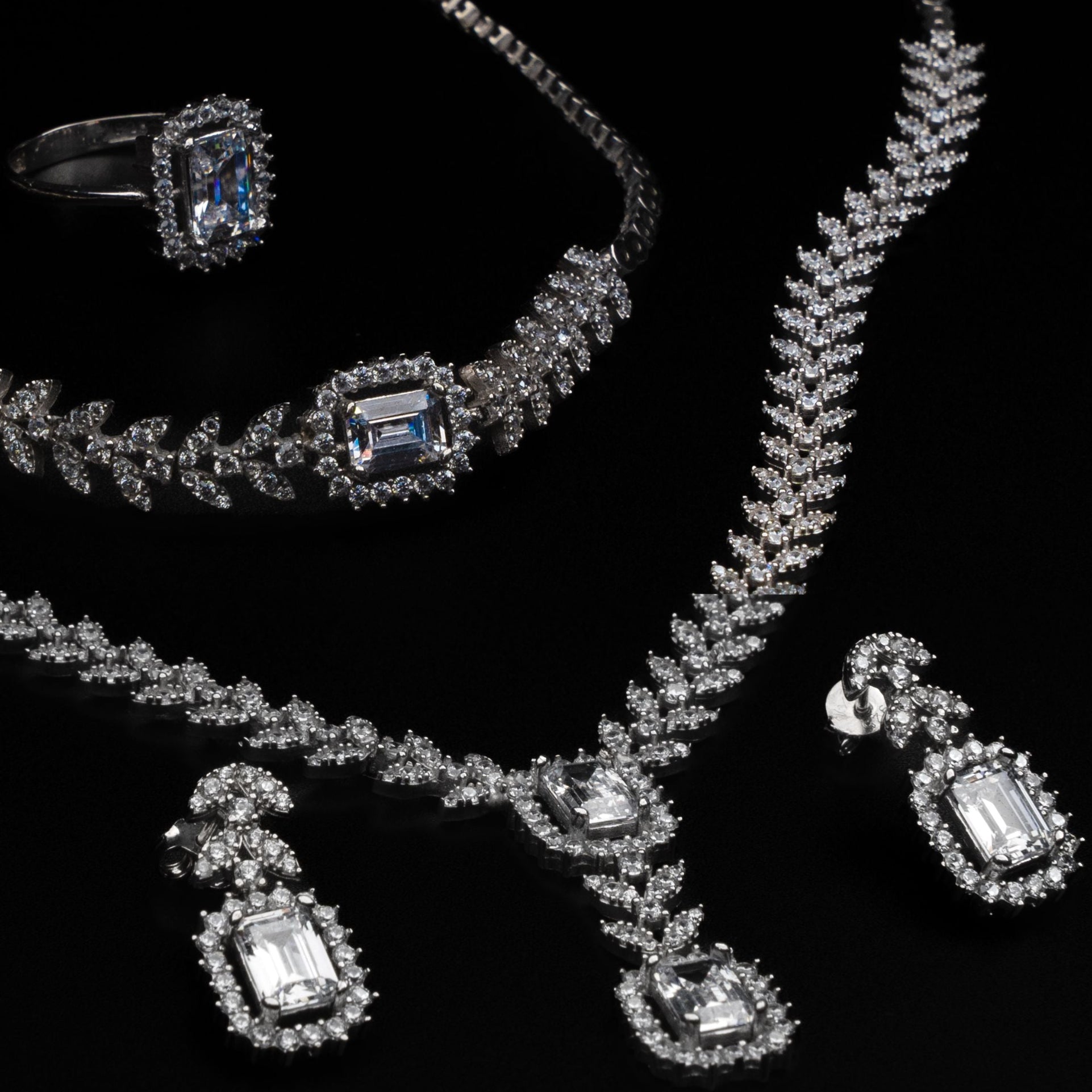 Jewelry set including a necklace, ring, and earrings on a black background